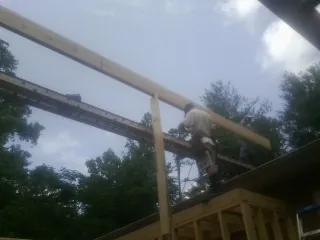 Carpenter setting a ridge beam over a new addition frame — Ice Dam Removal by Roofing Brothers in Boswell