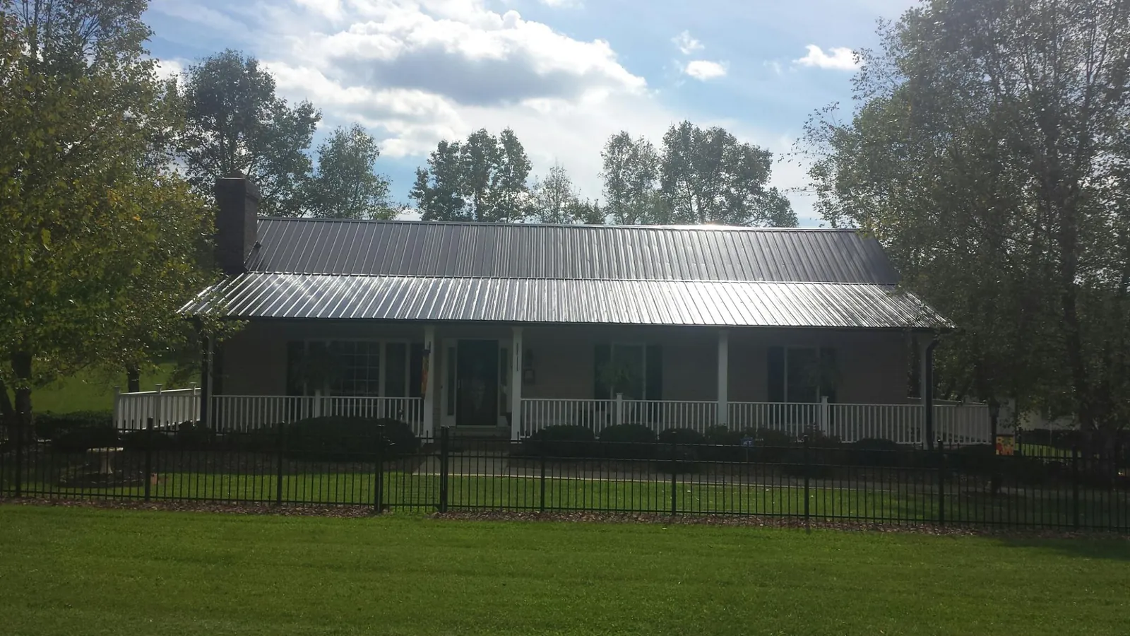 Gray metal roof on a brick ranch with a full width front porch — Gutter Guard Installation work by our crew in Boswell