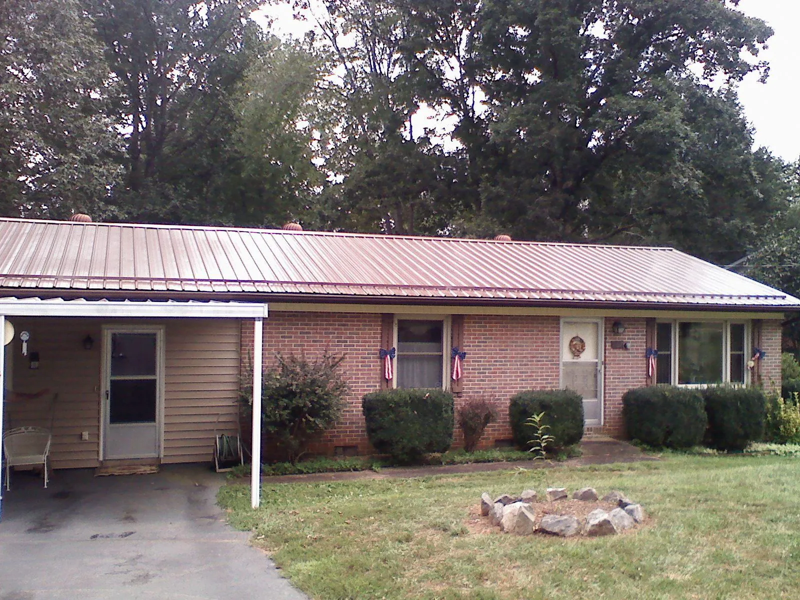 Bronze metal roof and carport on a brick ranch home — Roof Repair work by our crew in Boswell